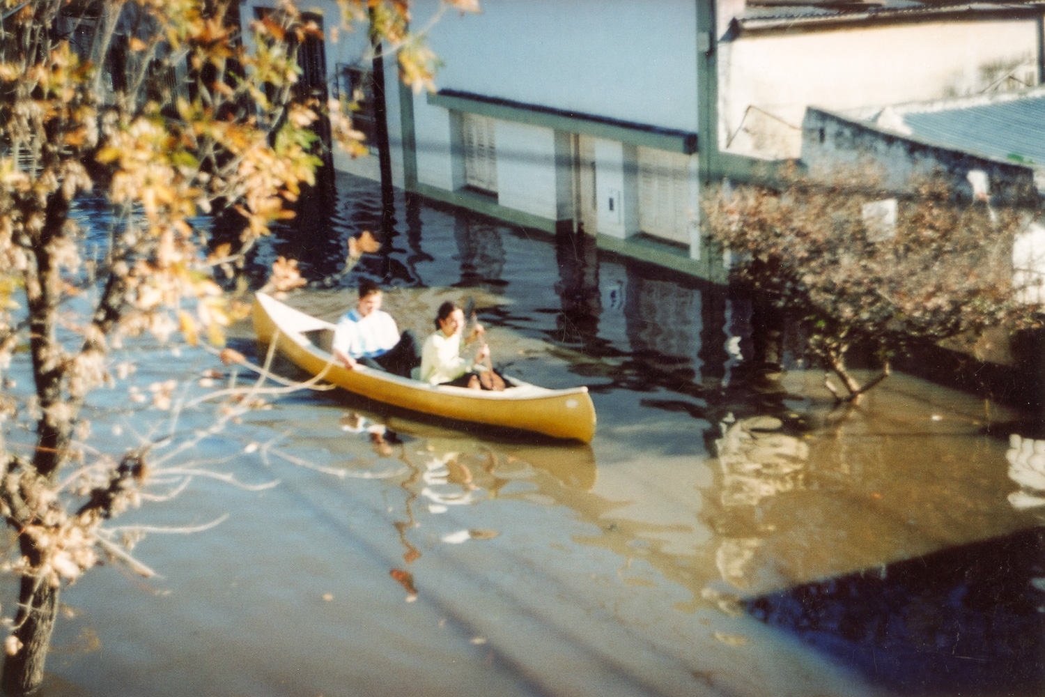 Dos jóvenes navegan en piragua por las calles inundadas.