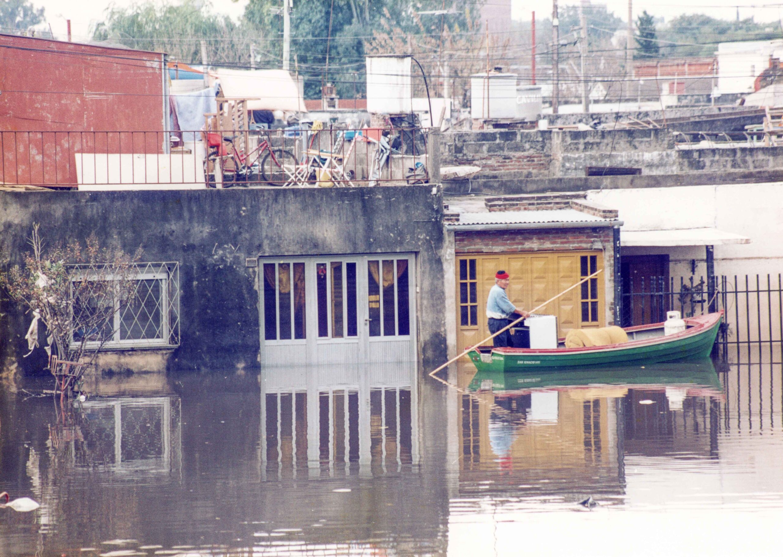 Hombre sobre una canoa recorriendo el barrio Chalet, llevando una garrafa, un electrodoméstico y un colchón enrollado